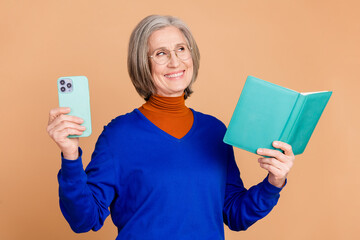 Photo of lovely pensioner lady hold device read book look empty space dressed stylish blue garment...