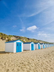 A vibrant row of colorful beach huts lines the sandy beach of Texel, Netherlands, creating a...