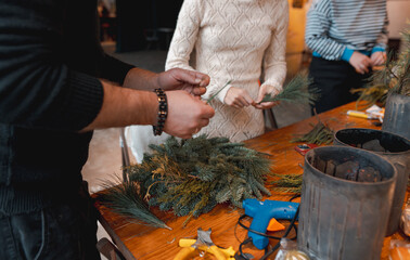 A young woman creating a Christmas wreath at a festive decoration workshop.