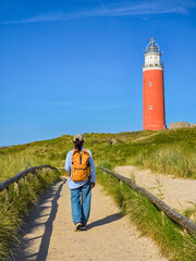 A man walking down a path with a majestic lighthouse standing tall in the background, guiding his...