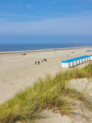 A tranquil beach setting with golden sand and charming huts nestled along the coast of Texel,...