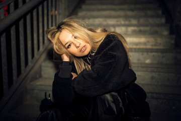 Caucasian attractive woman in black grunge attire posing on the staircase