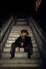 Caucasian attractive woman in black grunge attire posing on the staircase