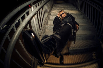 Caucasian attractive woman in black grunge attire posing on the staircase