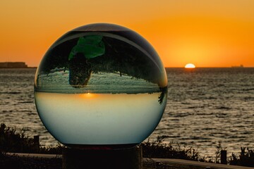 a ball that has been floating on the water with the sun setting in the background