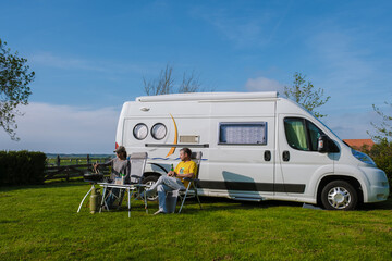 Two individuals enjoying a scenic moment of relaxation outside their camper van in Texel, Netherlands. a couple on a camping trip, camping at a farm in Texel Netherlands