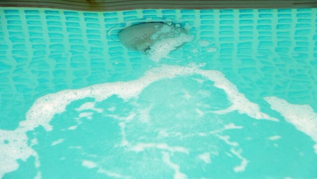A water jet is makes bubbles on the surface of the pool water