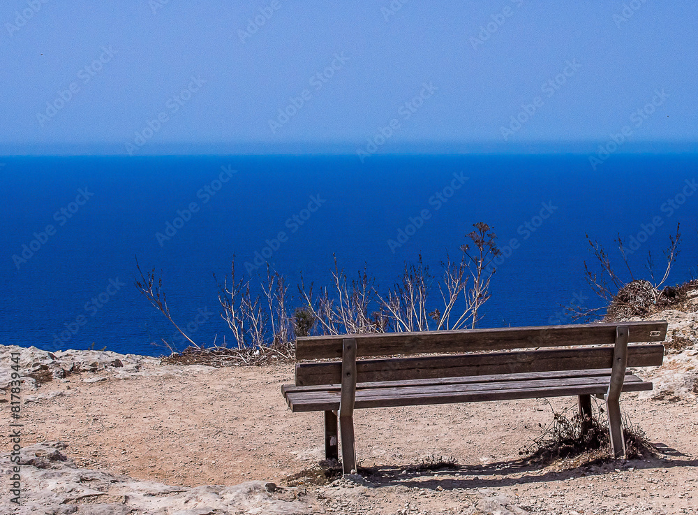 Wall mural View of the blue Mediterranean Sea seen from the coast of Malta with a bench in the foreground - Wall murals