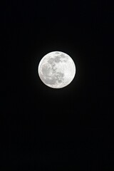 a bright full moon over a black sky with clouds in the foreground