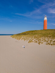 A majestic lighthouse stands tall on a sandy beach, guiding ships safely to shore with its bright...