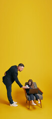 Father-Daughter Work Session. Father and daughter in formal attire working together. Dad helps daughter against sunny-yellow background. Concept of Father's day. Children's day, Family day, parenthood