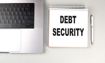 DEBT SECURITY text on notebook with laptop and pen