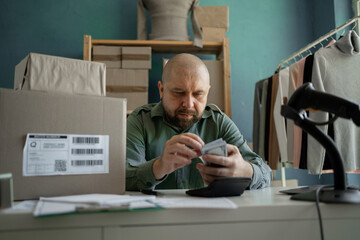 The seller counts the money from the delivery of goods. He holds dollars in his hands. Small...