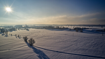 Aerial view of a winter landscape with a sunset casting a glow over a snow-covered field