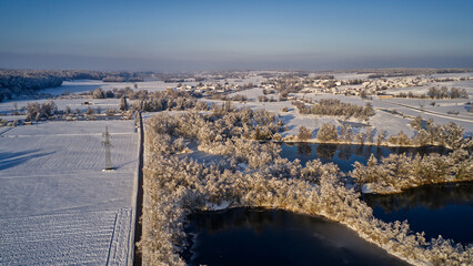 Aerial view of a winter landscape with a sunset casting a glow over a snow-covered field