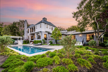 a house with a pool in front of it at sunset