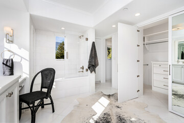 Large white bathroom with toilet, vanity, closet, and mirror