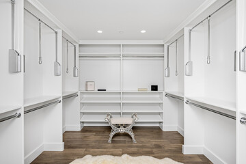 a modern white walk in closet with shelving and hanging racks