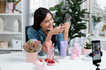 Young beautiful Asian girl reviewing moisturizing body lotion cream product to make glow skin...