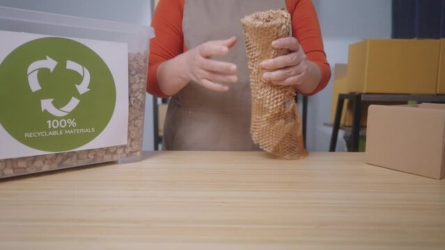 A woman wraps a product with eco-friendly honeycomb paper with label stating "100% Recyclable Materials" highlighting the sustainable practices of a small business, Slow Motion Shot