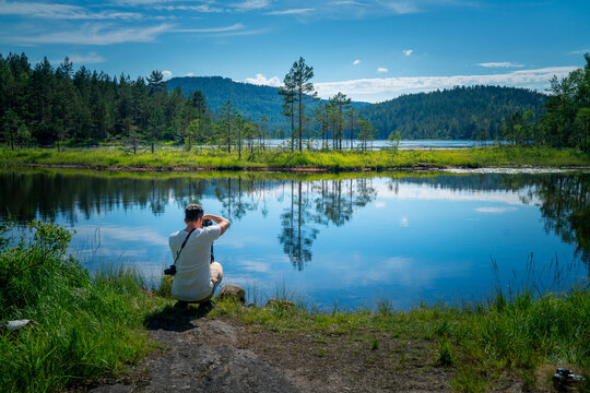 Summer Serenity:Traveler overlooking Reflective Mire in Norway's Stunning Landscape
