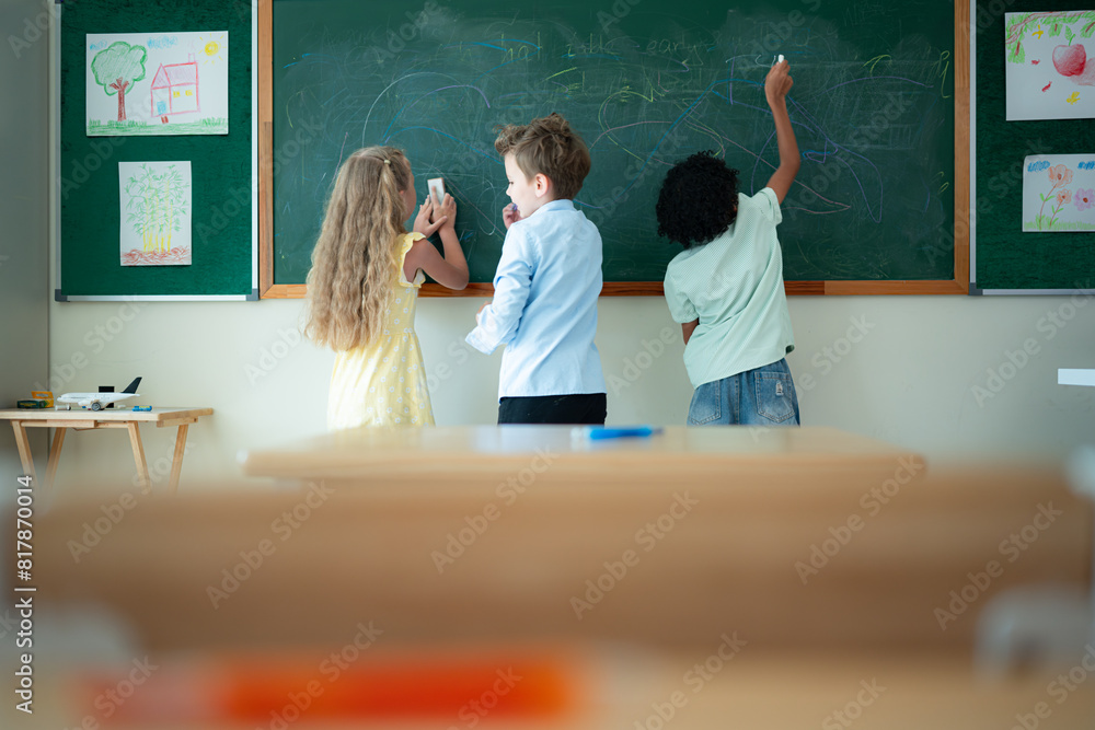 Wall mural Before beginning their academic day, Children like writing on the chalkboard.