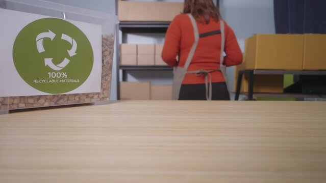 The focus is on a container labeled "100% Recyclable Materials" filled with eco-friendly cushioning made from water hyacinth highlighting the sustainable practices of a small business