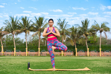 Young indian woman do yoga meditation exercise outdoor at summer park, mental health, Fitness and healthcare, Sustainable lifestyle. 