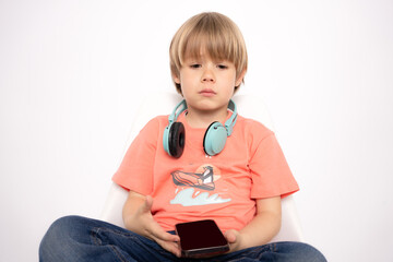Preschooler boy upset by losing in a mobile game. Sad child using Smart mobile phone while sitting...