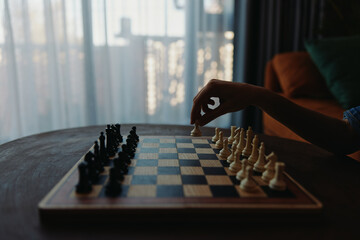 Strategic thinking Person playing chess game on a table in front of a window, contemplating moves