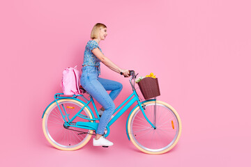Full size profile photo of pretty young girl ride bike empty space wear top isolated on pink color...