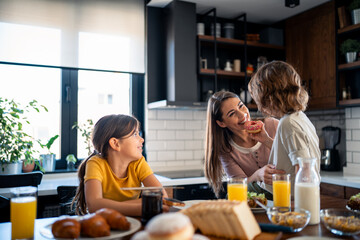 Two kids, little boy and girl spending time with mother, eating breakfast at kitchen table. Happy...