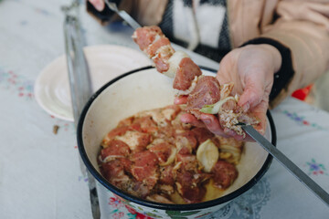 woman hands and marinated pork shashlik on skewers