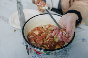 woman hands and marinated pork shashlik on skewers