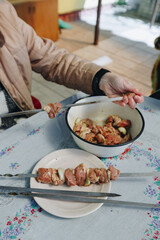 woman hands and marinated pork shashlik on skewers