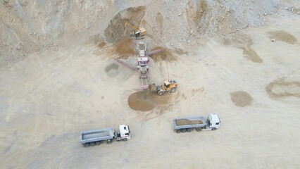 Aerial of truck tractor excavator crane working extracting minerals from stone rock quarry cave....
