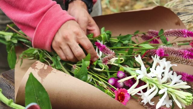Closeup footage of the gardener hands making a flower bouquet outdoor during daytime