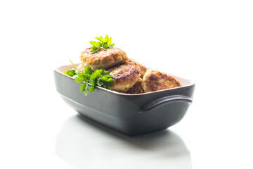 fried meat cutlets in a ceramic form on a wooden table