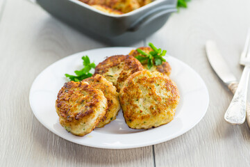 fried meat cutlets in a ceramic form on a wooden table