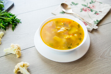 Homemade chicken vegetable soup on rustic wooden background