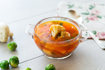 vegetable soup with Brussels sprouts and cauliflower, in a glass plate on a wooden table