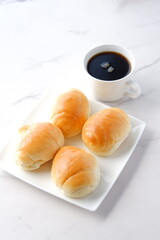 焼きたてのバターロールと淹れたてのコーヒーが用意された朝食のテーブル