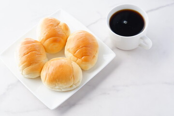 焼きたてのバターロールと淹れたてのコーヒーが用意された朝食のテーブル