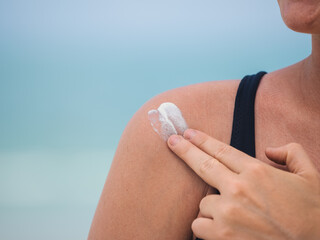 Woman Applying Sunscreen on Shoulder at the Beach for Skin Protection