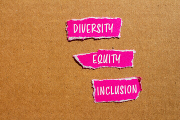 Diversity, equity and inclusion words written on ripped pink paper pieces with cardboard...