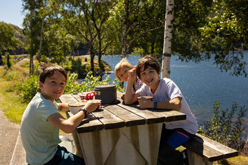 Children, brothers, eating lunch on a public rest stop in Norway, amazing nature around