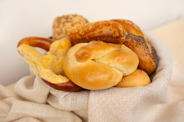 wicker basket overflowing with freshly baked pastries: cheese and poppy seed buns, pretzels, and sweet curd tarts