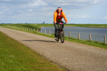 National Park in Holland. Landscape in spring on a sunny day. Cyclist on dam. Netherlands, Zeeland, Oosterschelde.