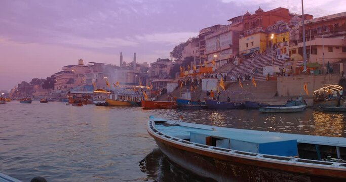 Varanasi, Uttar Pradesh, India. Many Boats moored on Ganga river near ghats. Hundreds of tourists and locals come in boats to watch Ganga Maha Aarti ceremony and the fire ceremony. Purple sunset sky