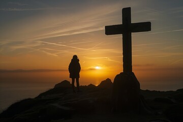 A silhouette of a person standing beside a large cross atop a hill during a vibrant sunset, overlooking a tranquil ocean horizon.